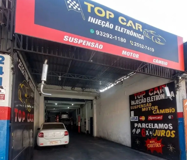 Entrada da oficina vista da calçada, com carro dentro do box